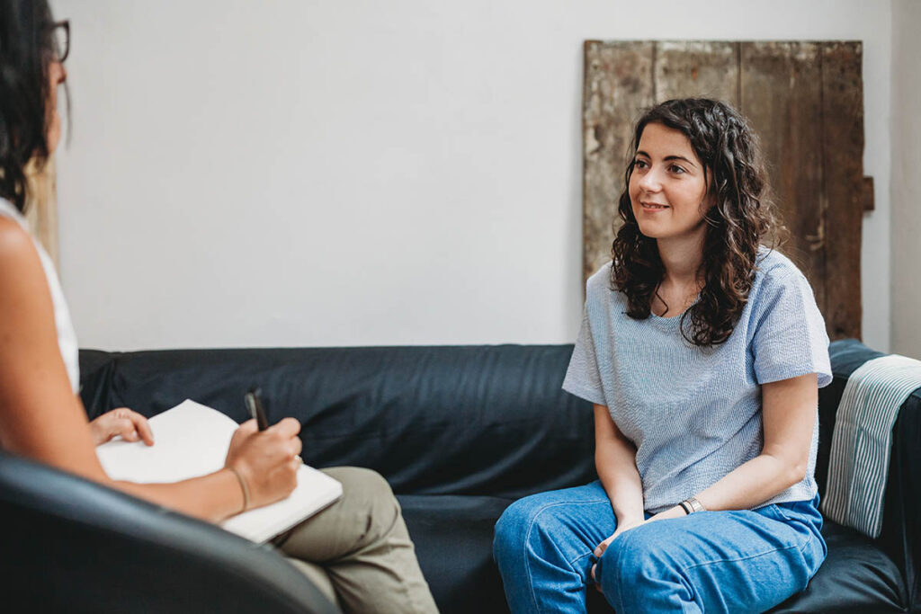 Woman on couch discussing the benefits of an IOP with a therapist